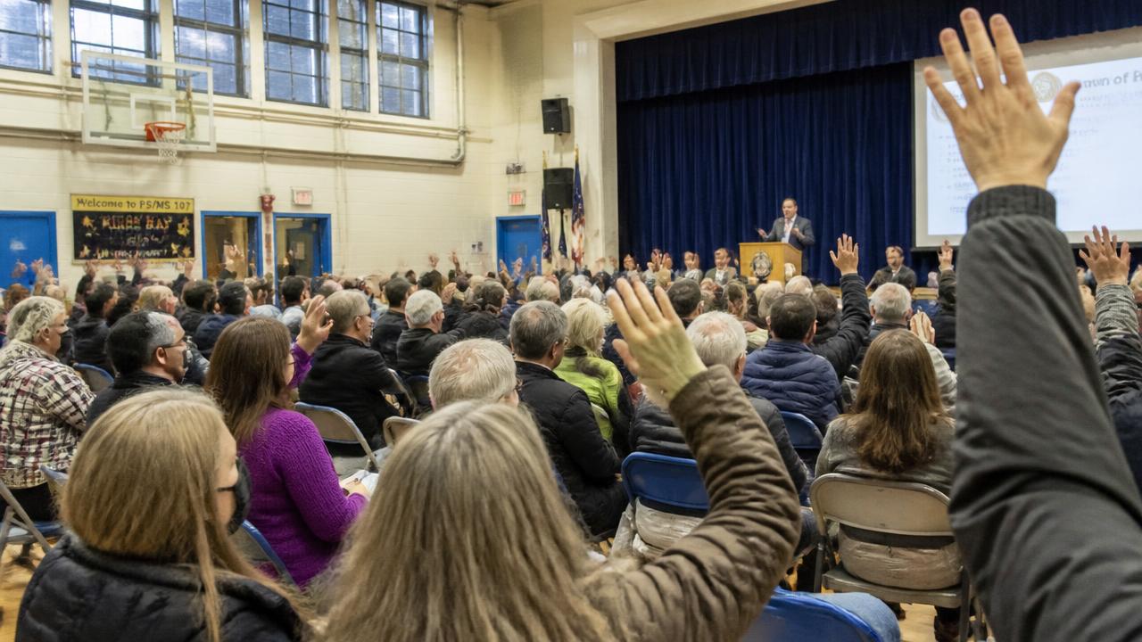 Crowded community town hall meeting with residents raising their hands